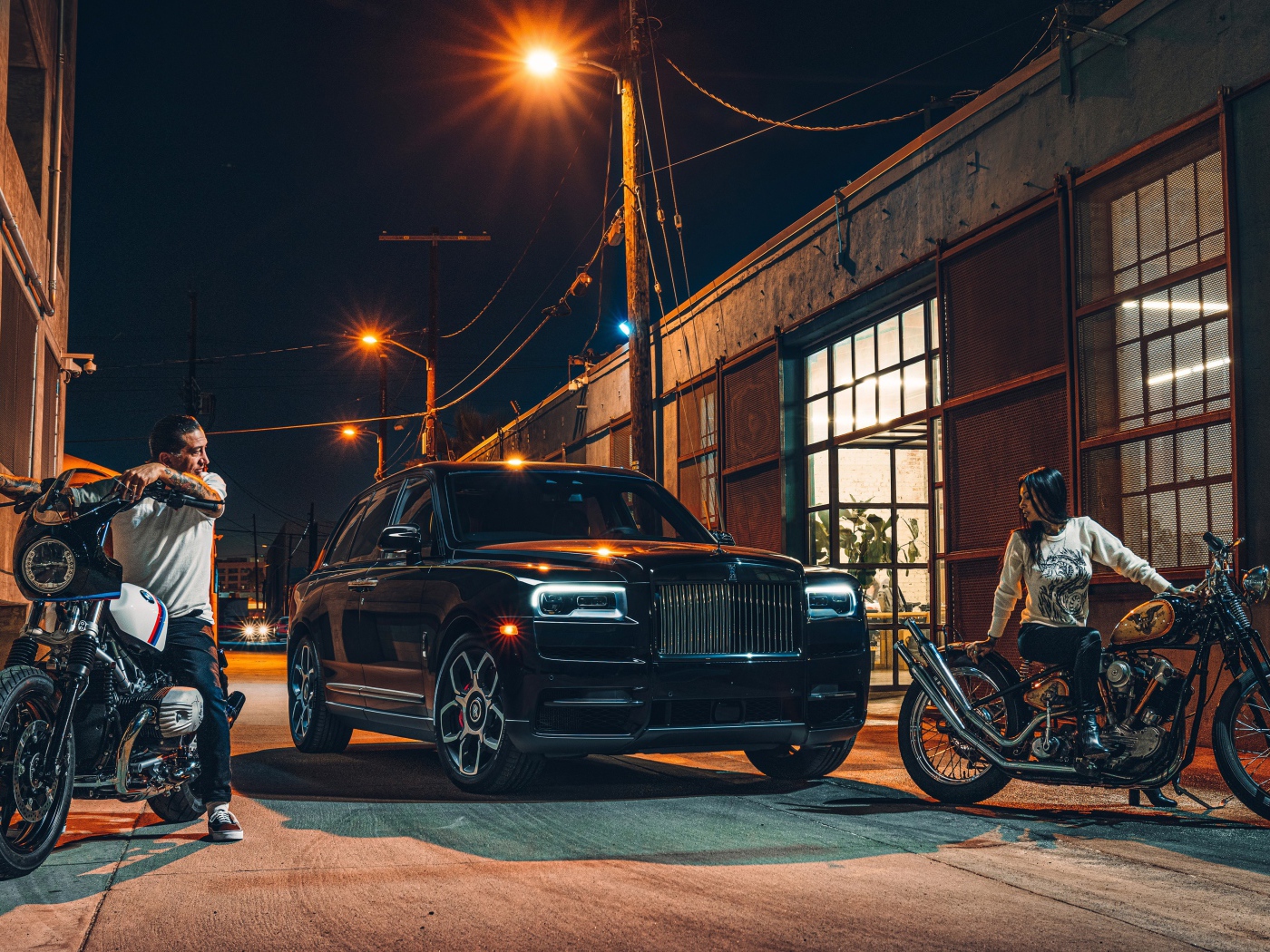 Черный стильный автомобиль Rolls-Royce Cullinan на улице города с байкерами