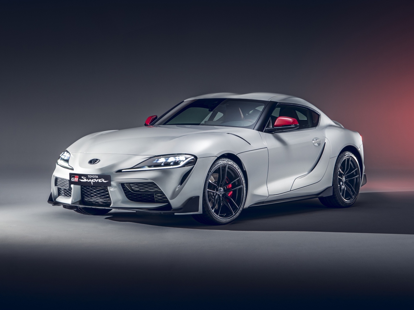 Серебристый автомобиль Toyota GR Supra 2L 2020 года на сером фоне