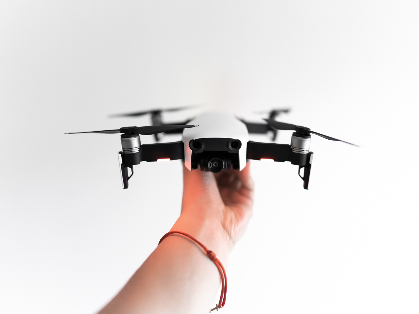Белый квадрокоптер в руке на белом фоне