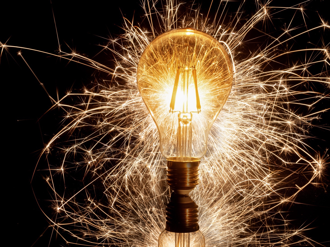 Зажженная лампа на черном фоне с искрами 
