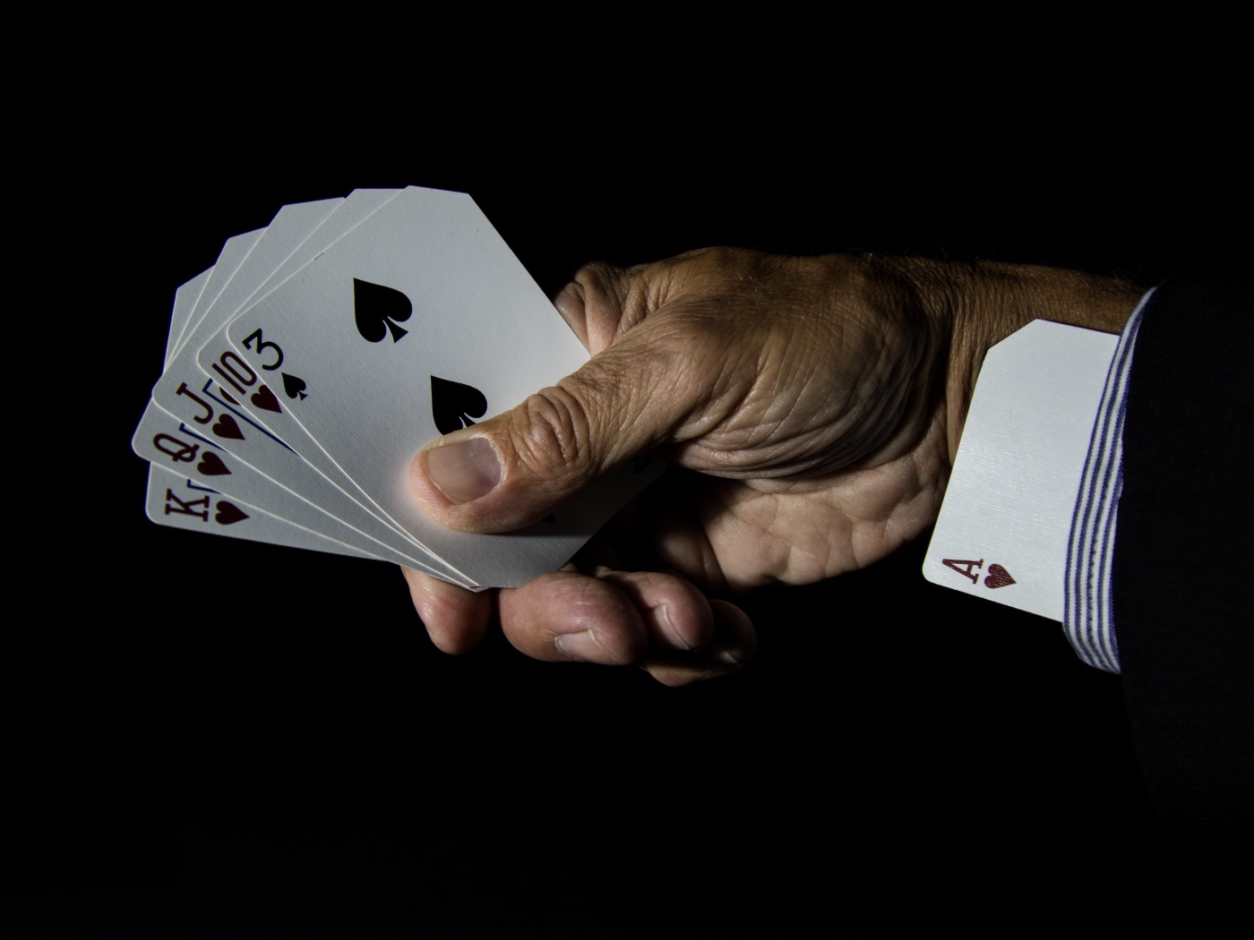 Туз в рукаве у шулера на черном фоне 