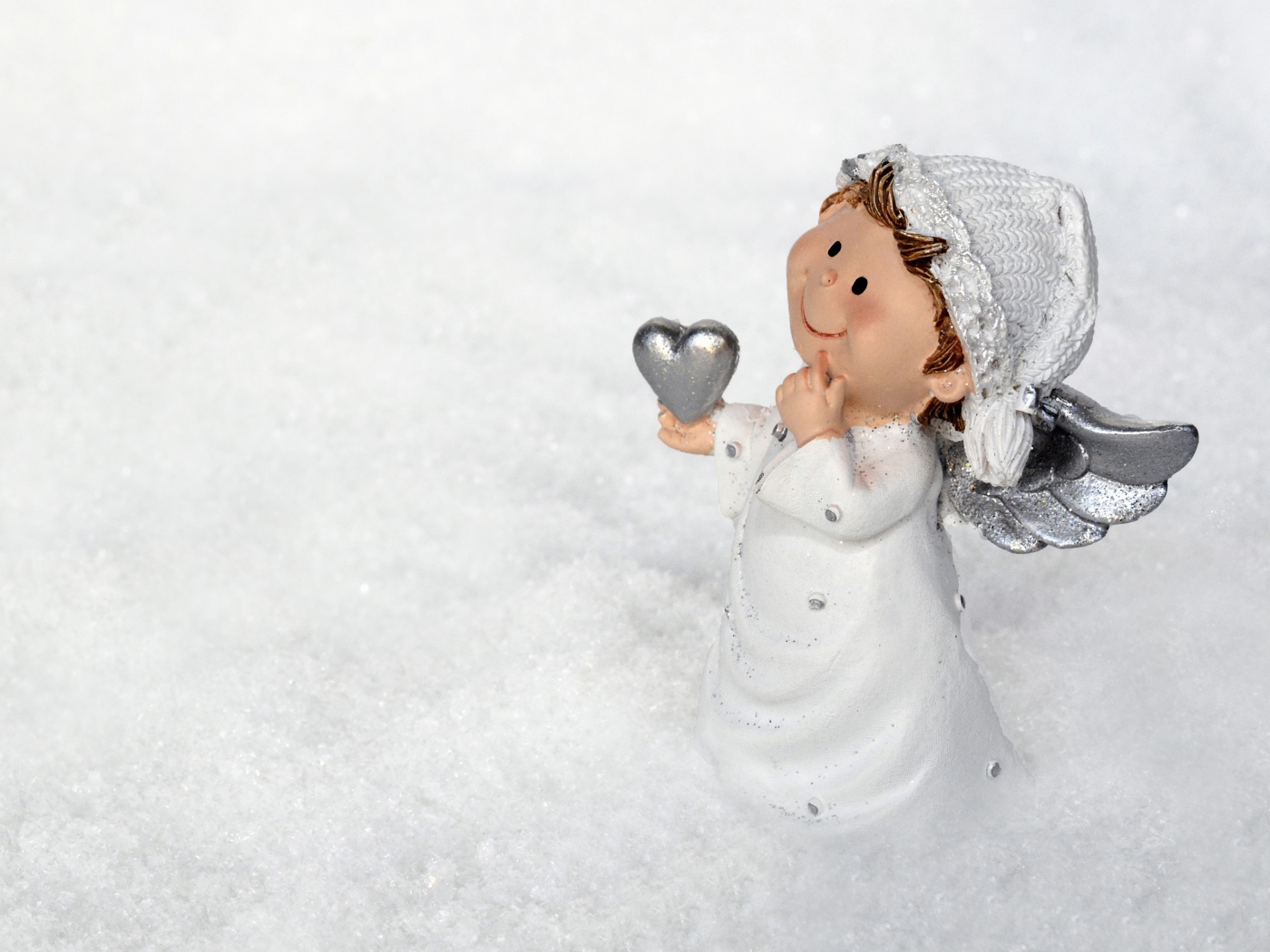 Статуэтка ангела стоит на снегу 