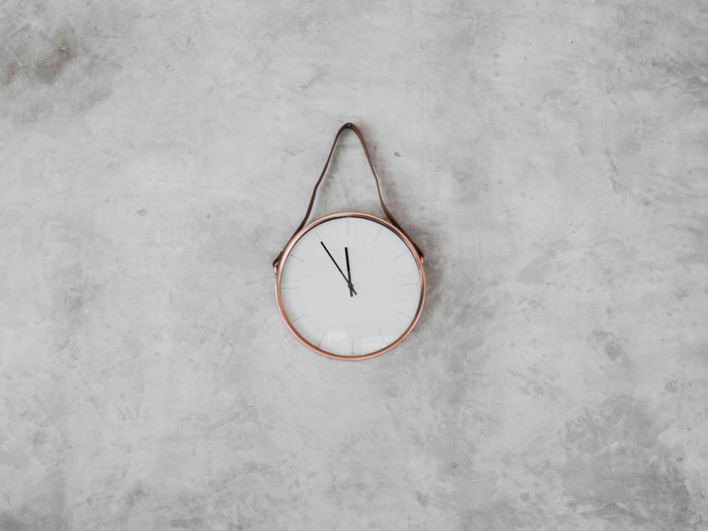 Часы с черными стрелками висят на серой стене 