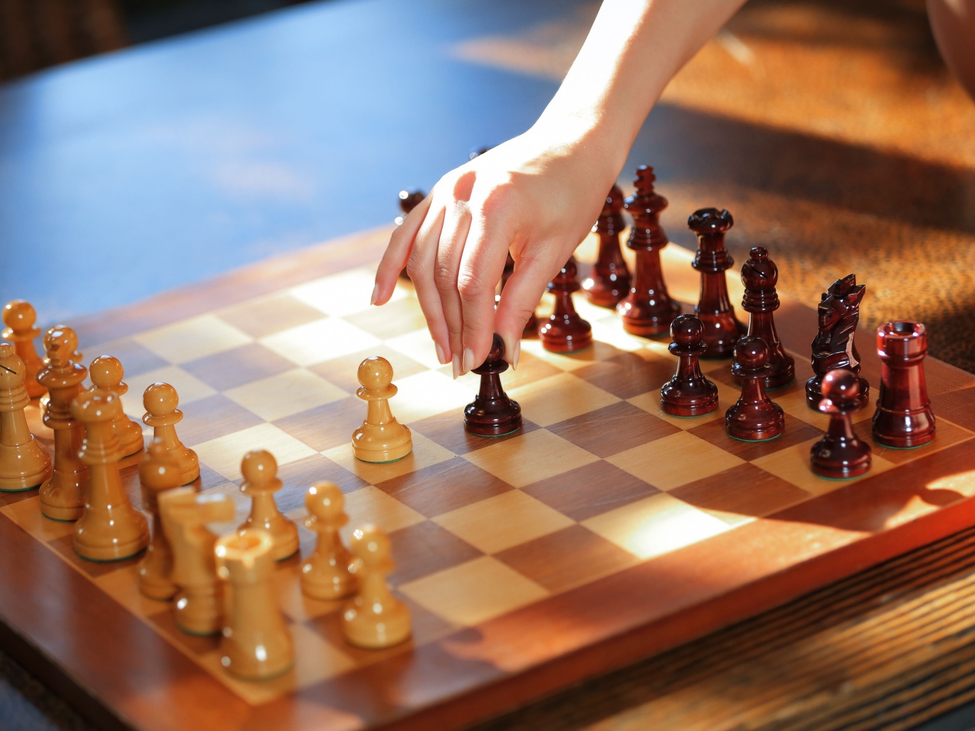 Женская рука переставляет шахматы на доске 