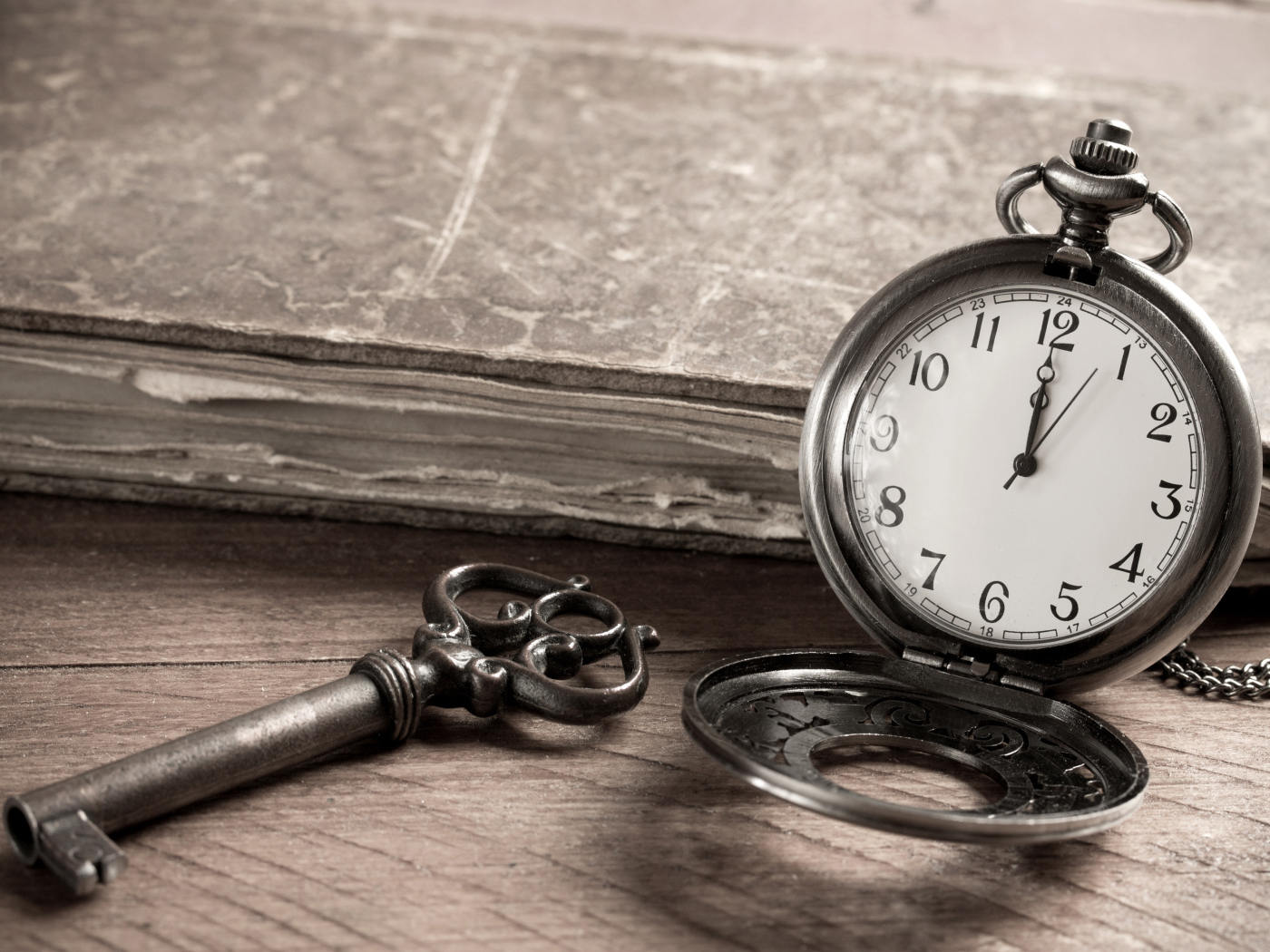 Карманные часы на столе с ключом и старой книгой 