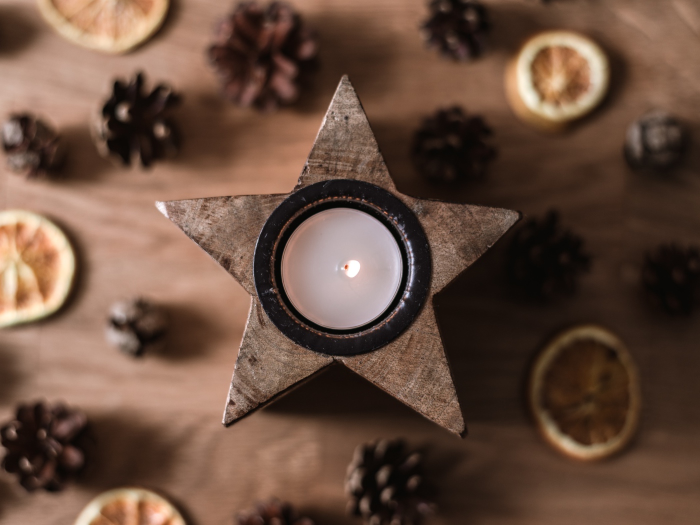 Star shaped candle on table with pine cones and dried orange