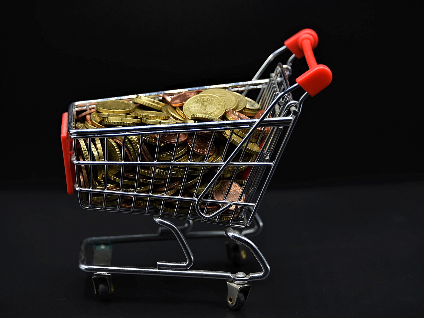 Железная тележка с монетами на черном фоне 