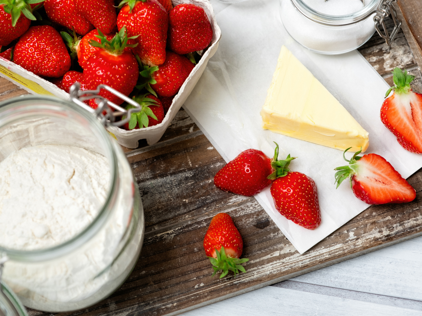 Кусок масла на столе с клубникой и мукой 