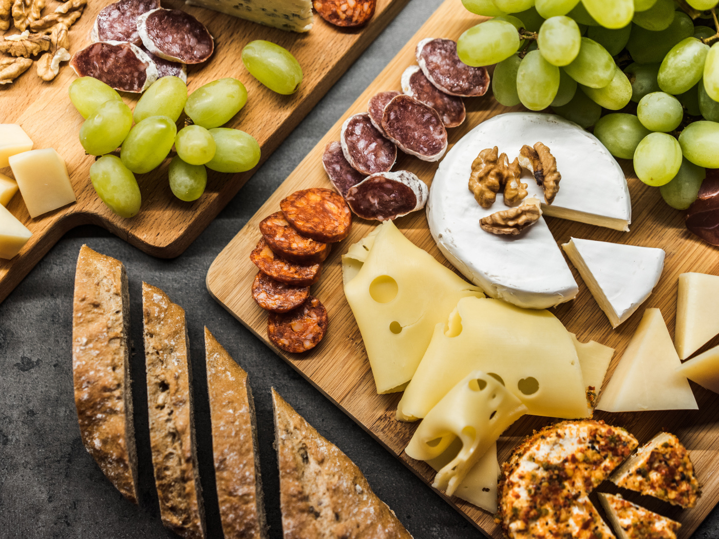 Сыр, колбаса, виноград и батон  на столе 