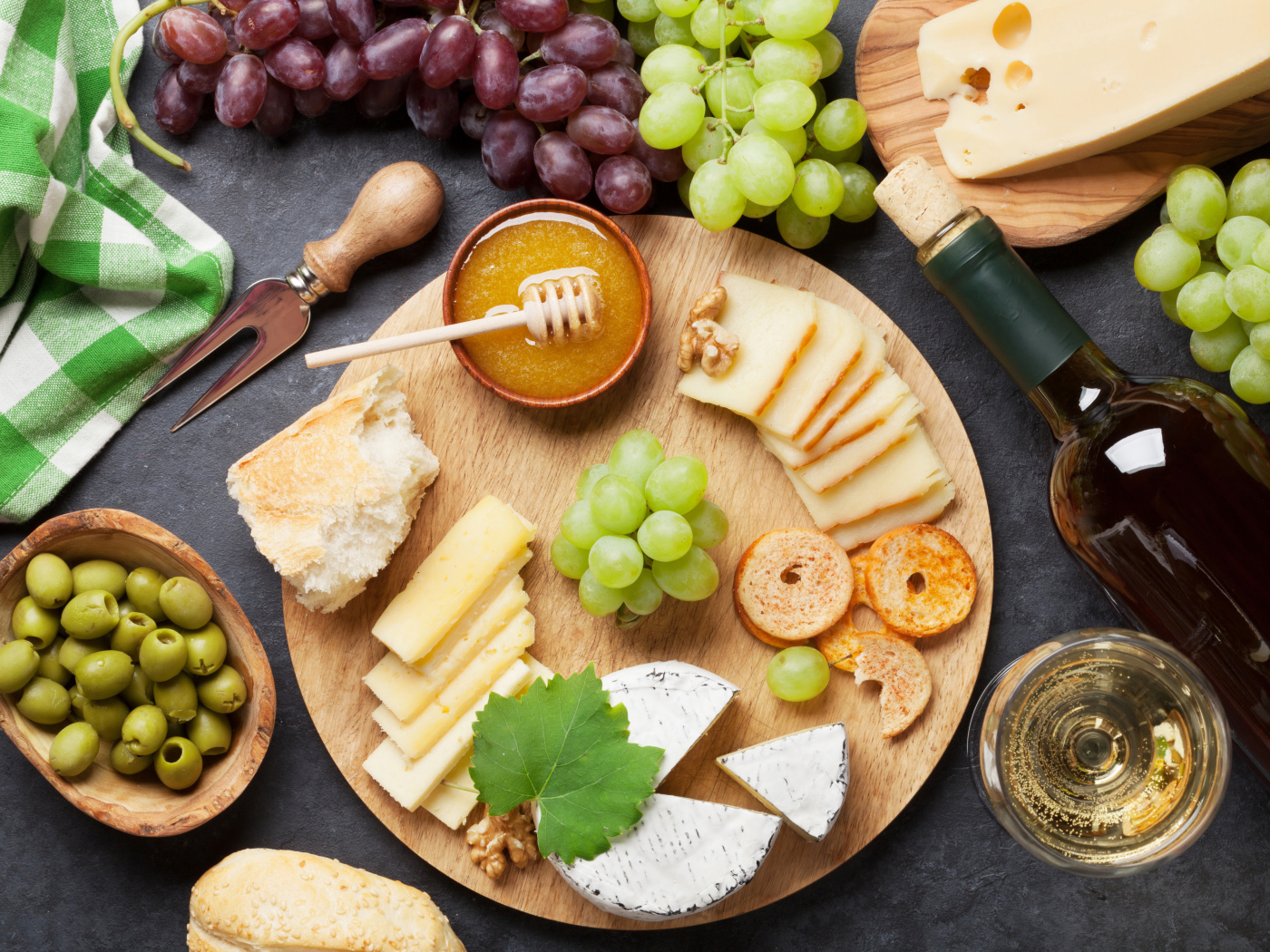 Сыр на столе с виноградом, оливками и белым вином