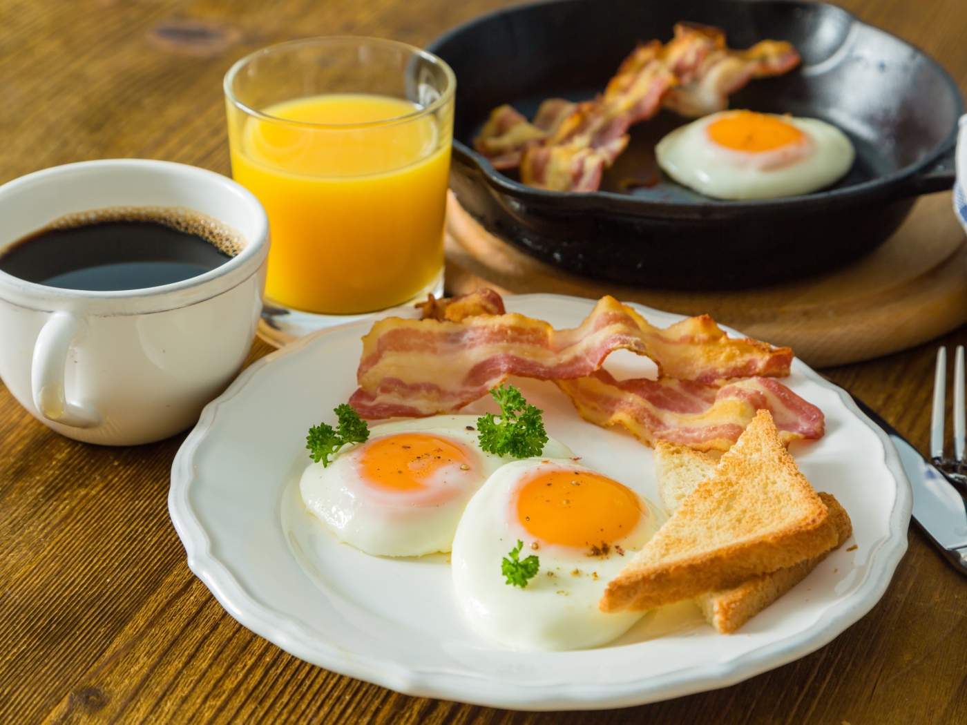 Яичница с беконом и тостами на столе с соком и кофе