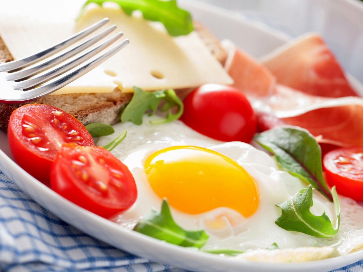 Яичница с помидорами на тарелке с ветчиной и бутербродом