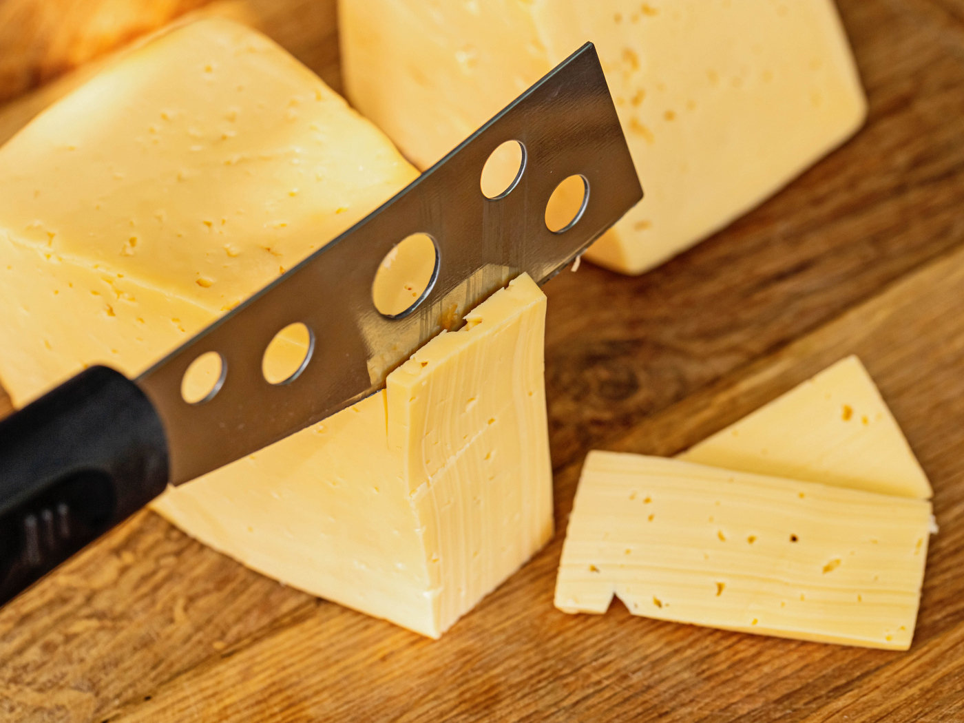 Твердый сыр с ножом на столе