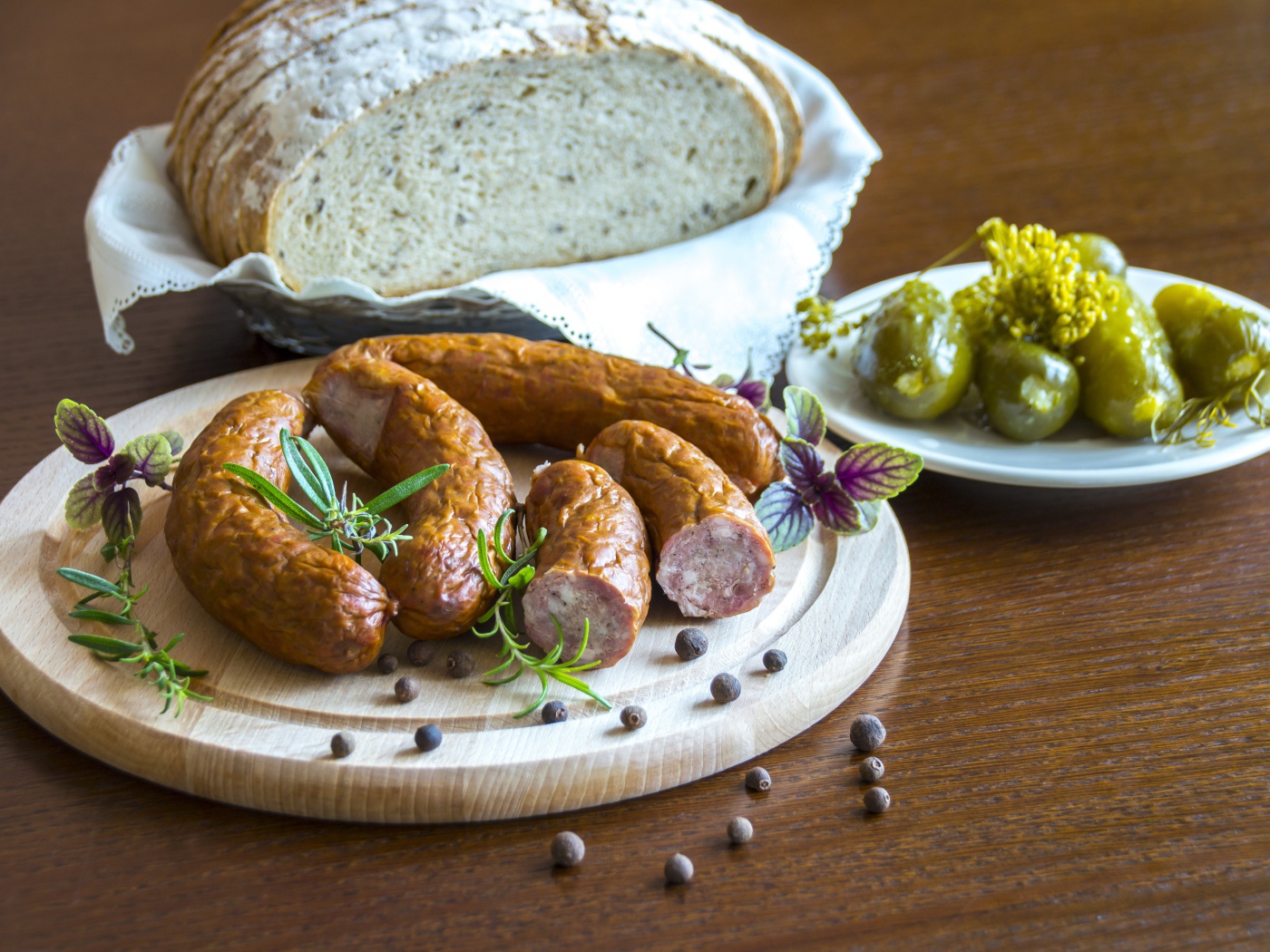 Домашняя колбаса на столе с хлебом и маринованными огурцами