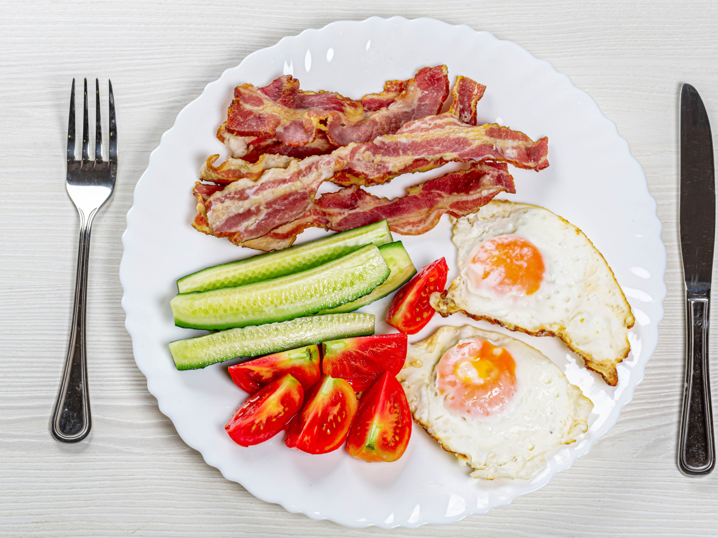 Большая белая тарелка с беконом, огурцами, помидорами и яичницей 