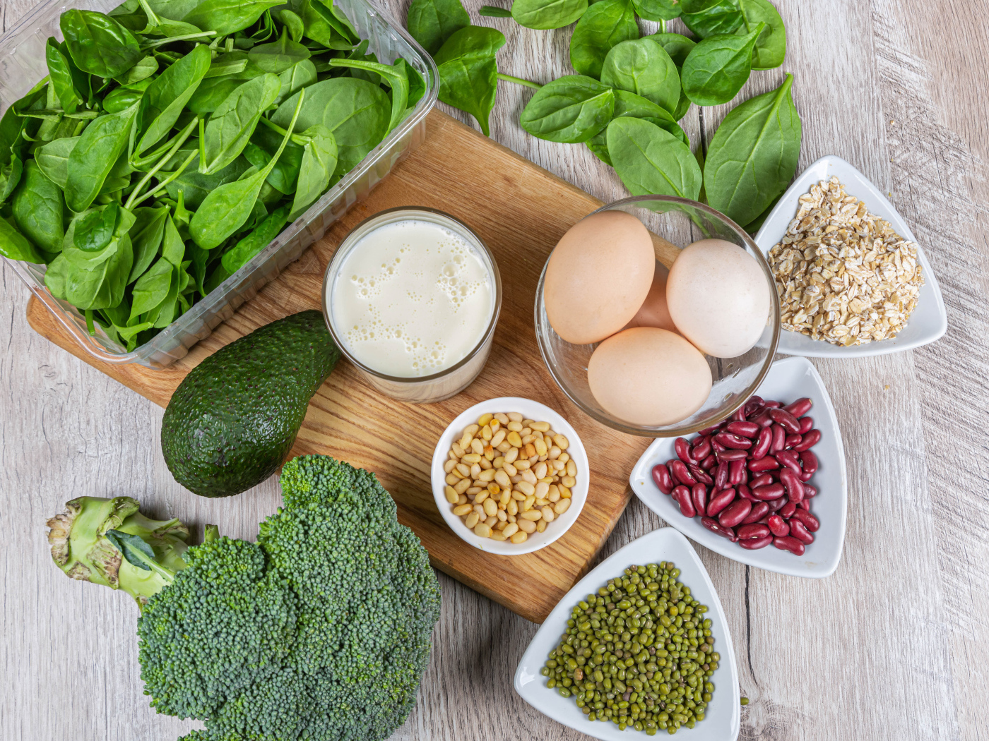 Бобовые, авокадо, базилик, яйца молоко и брокколи на столе
