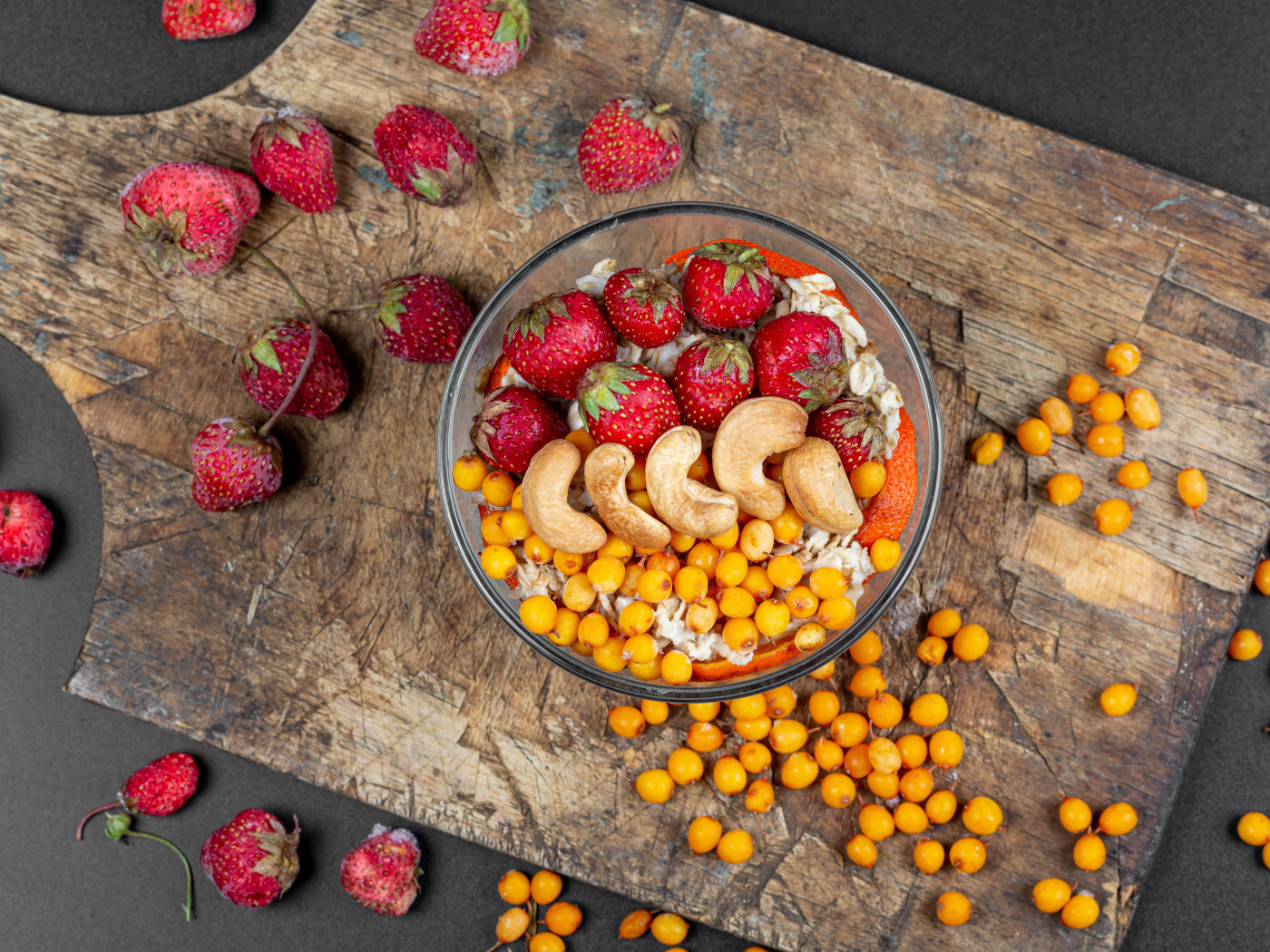 Мюсли с клубникой, орехами и облепихой на доске 