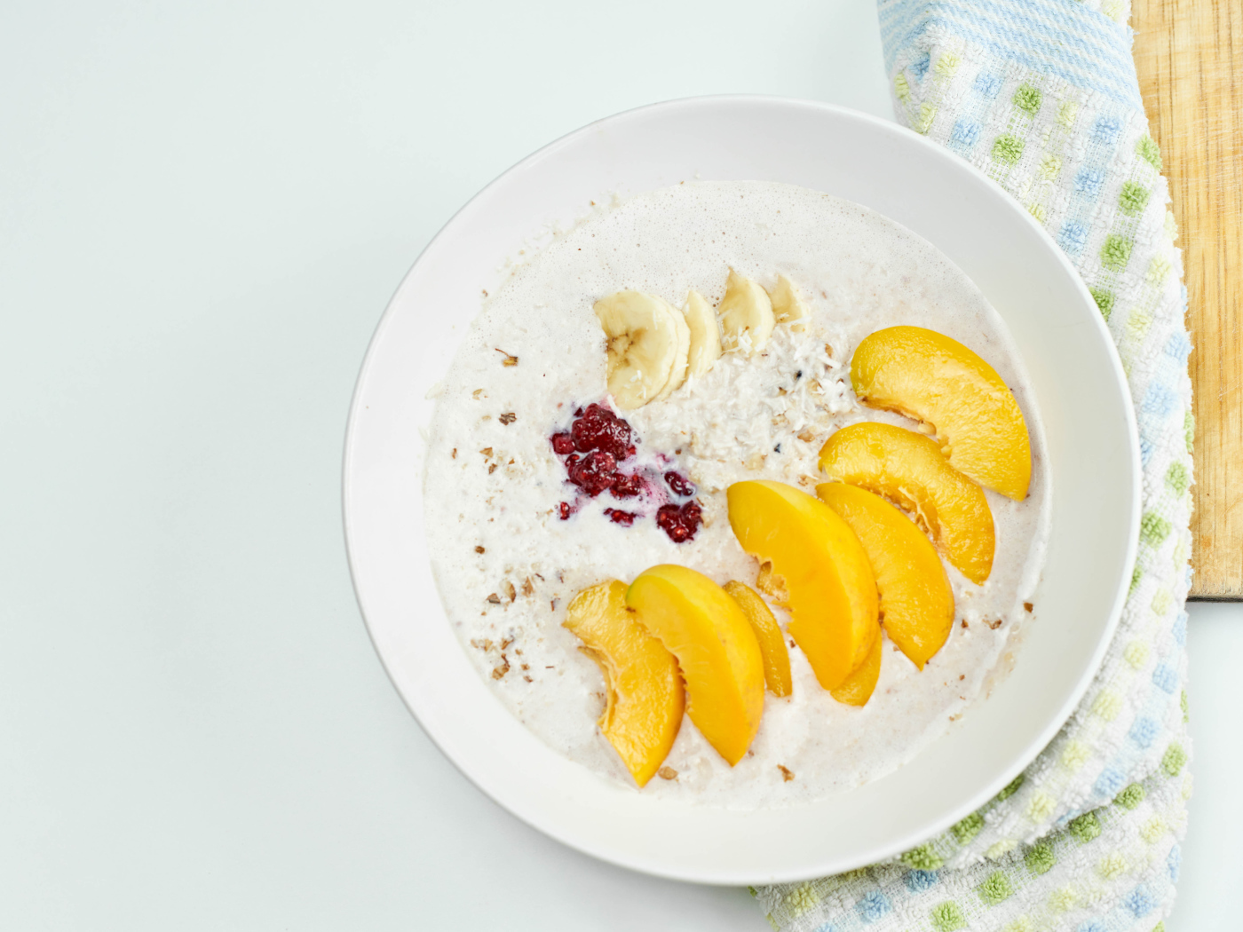 Мюсли с йогуртом в тарелке с кусочками банана и персика