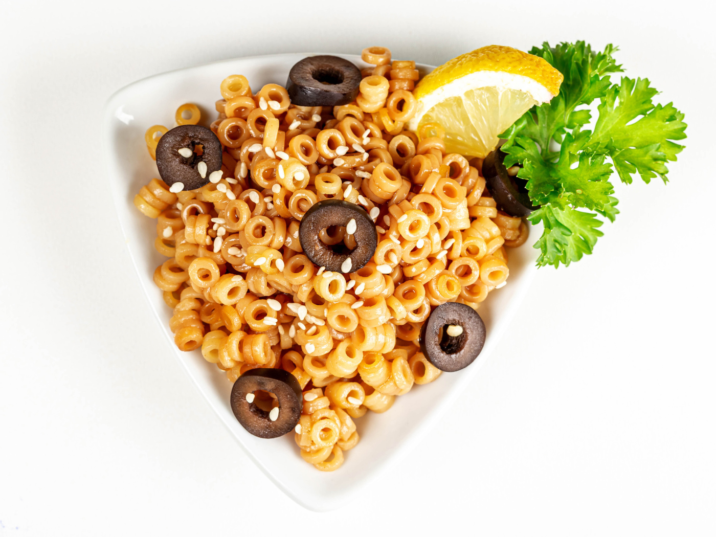 Макароны на тарелке с оливками и лимоном