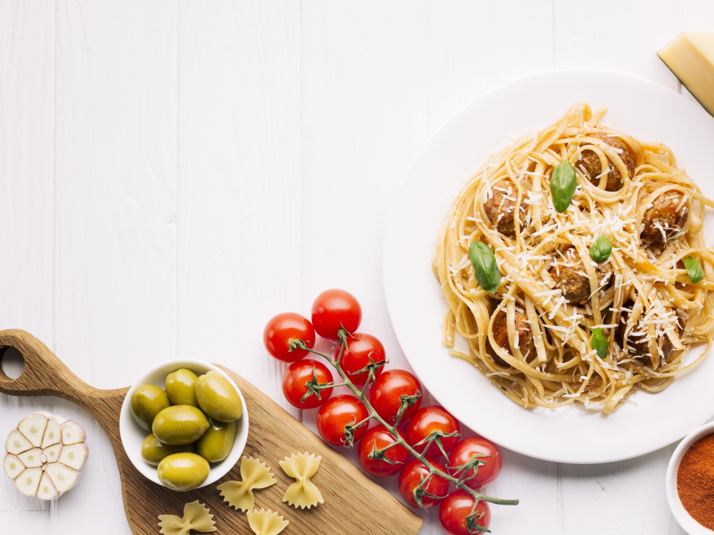 Паста с фрикадельками на столе с помидорами и оливками