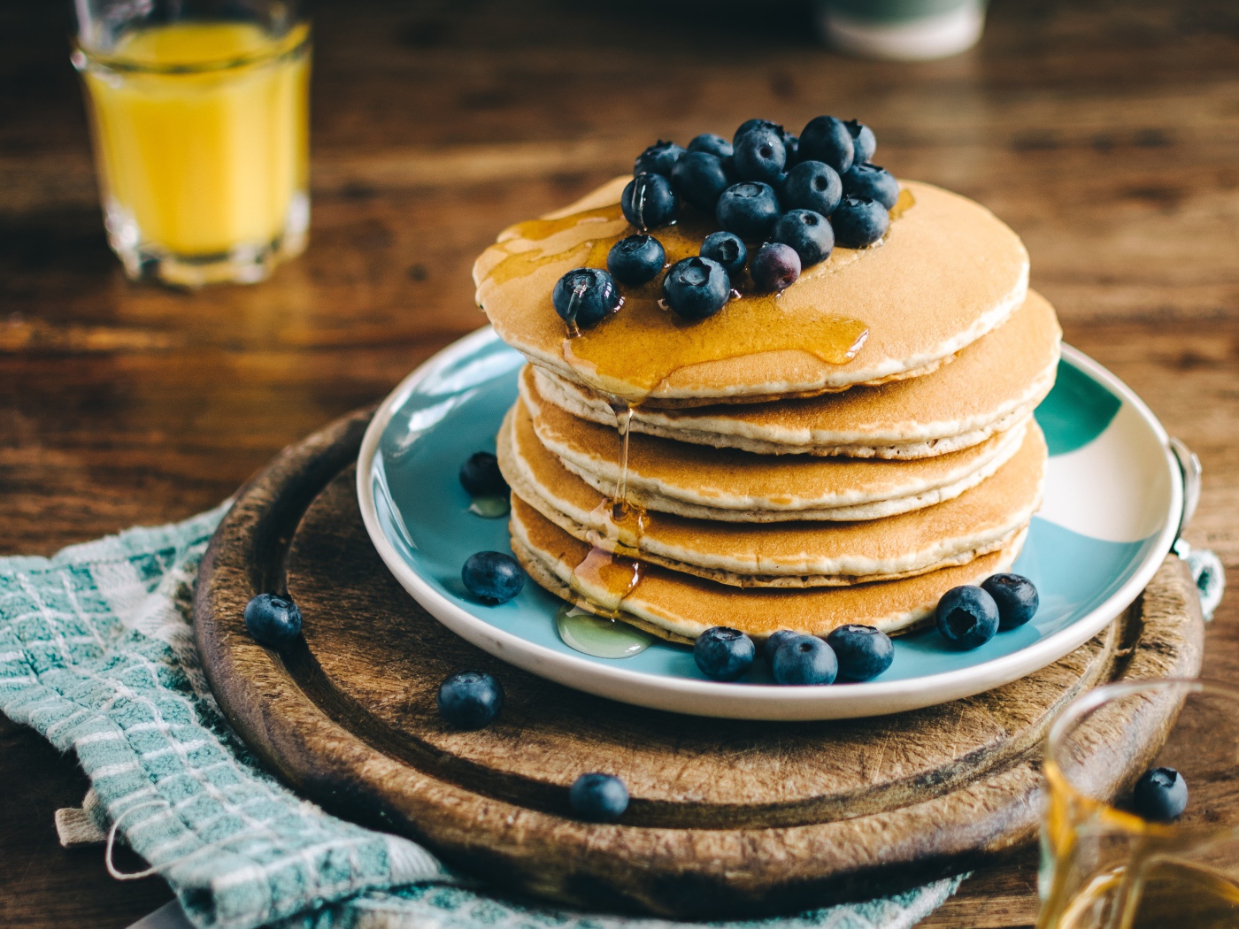 Румяные оладья на тарелке  с медом и ягодами черники 