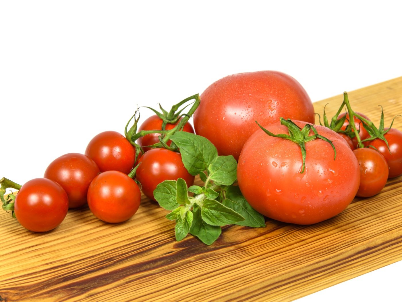 Small and large tomatoes on a wooden board