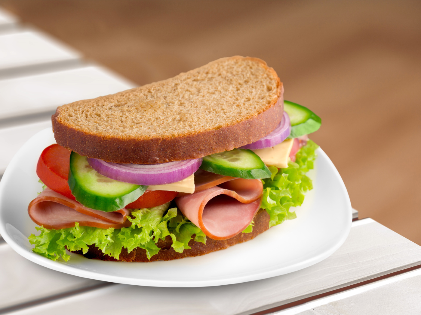 Вкусный аппетитный бутерброд с овощами и ветчиной на тарелке 