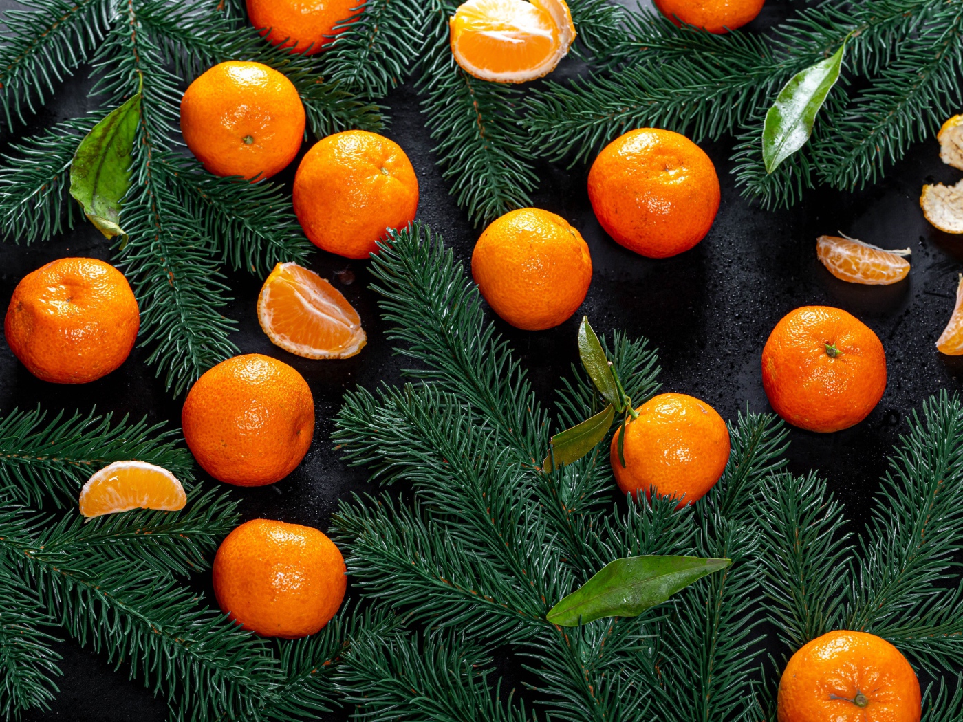 Много мандаринов на столе с еловыми ветками