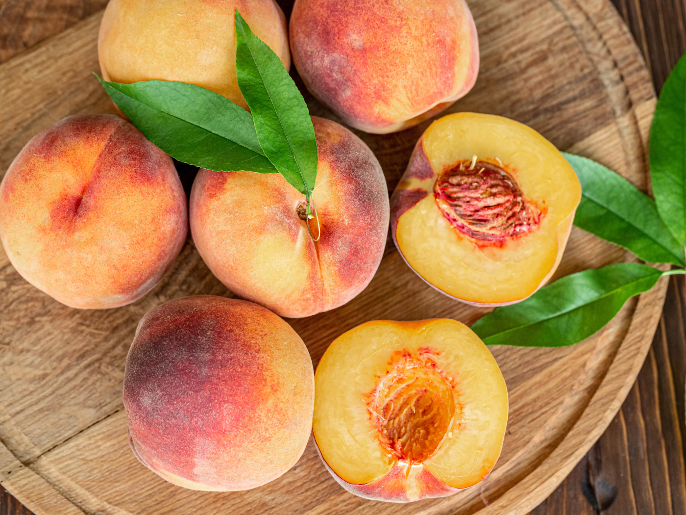 Аппетитные свежие персики на деревянной доске