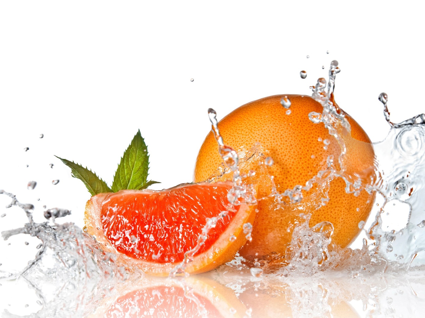 Большой спелый апельсин в брызгах воды на белом фоне