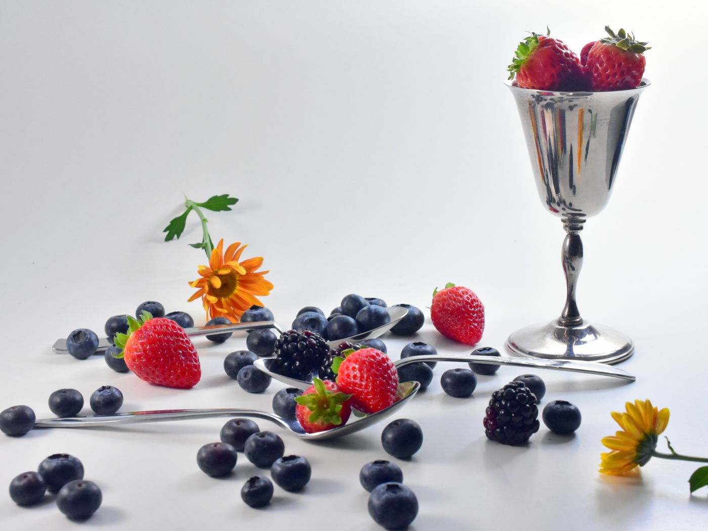 Ежевика, черника и клубника на столе с ложками