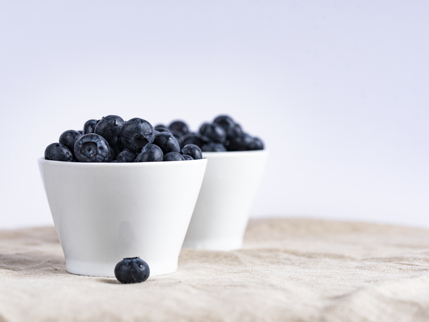 Синие ягоды черники в белой посуде на столе 