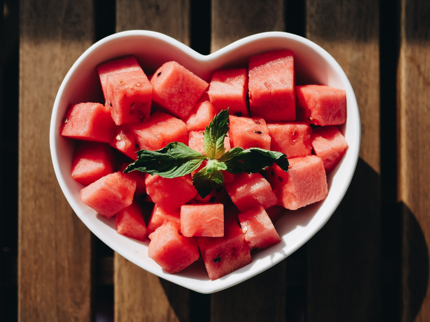 Нарезанный кубиками арбуз в белой тарелке в форме сердца
