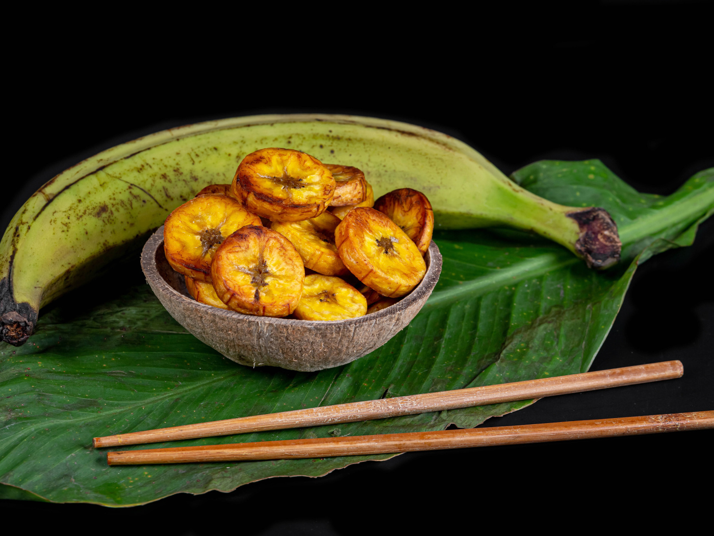 Сушеные бананы на столе с палочками и зеленым листом