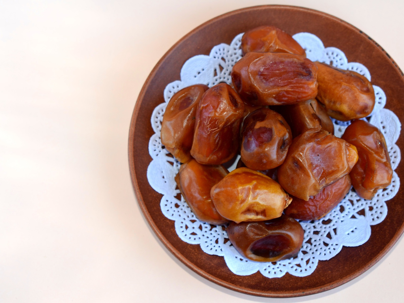 Сушеные финики в деревянной миске на белом фоне