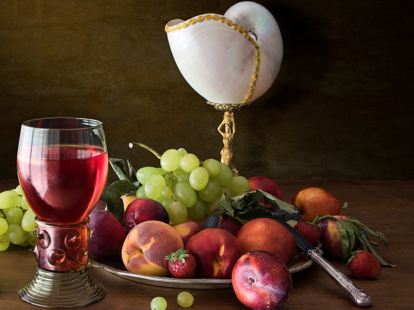 Свежие фрукты и ягоды на столе с вином и лампой 