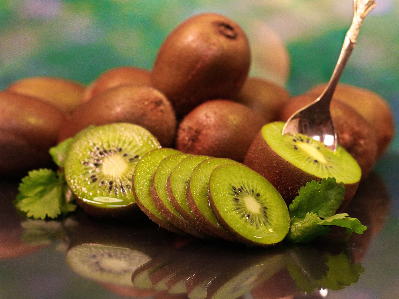 Many ripe kiwi fruits on the table with a spoon