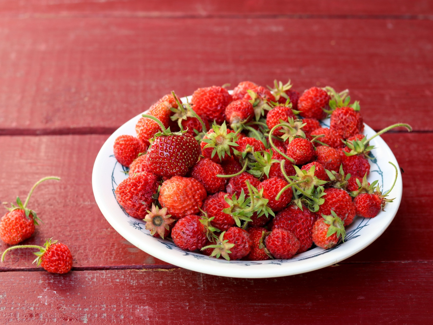Тарелка со спелой домашней клубникой на столе