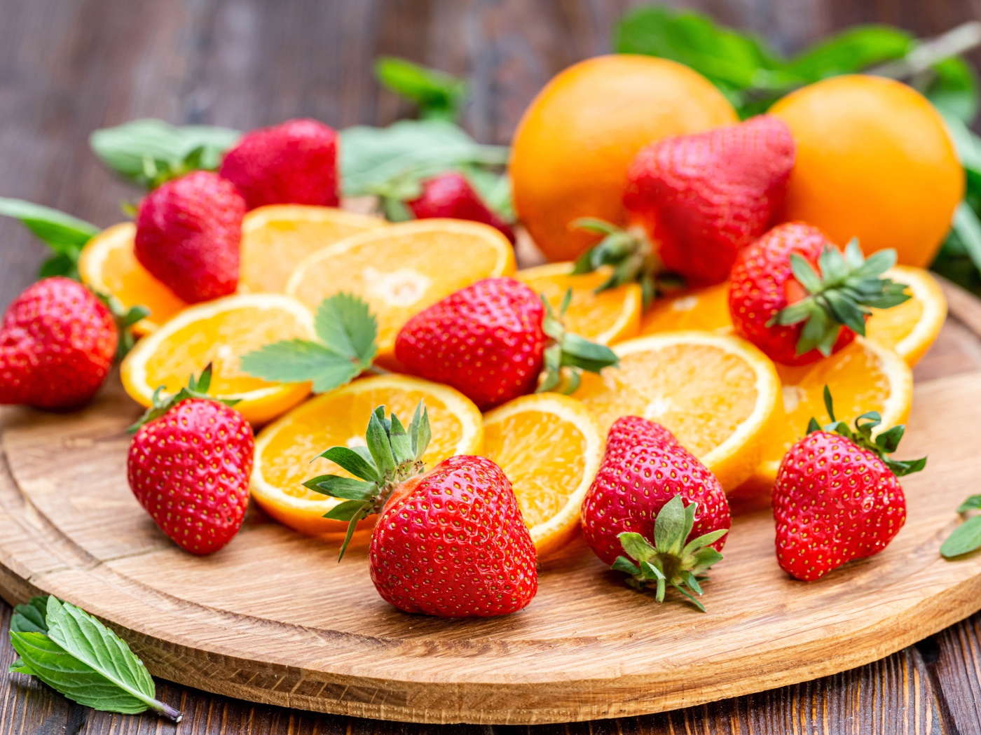Красная свежая клубника на доске с кусочками апельсина