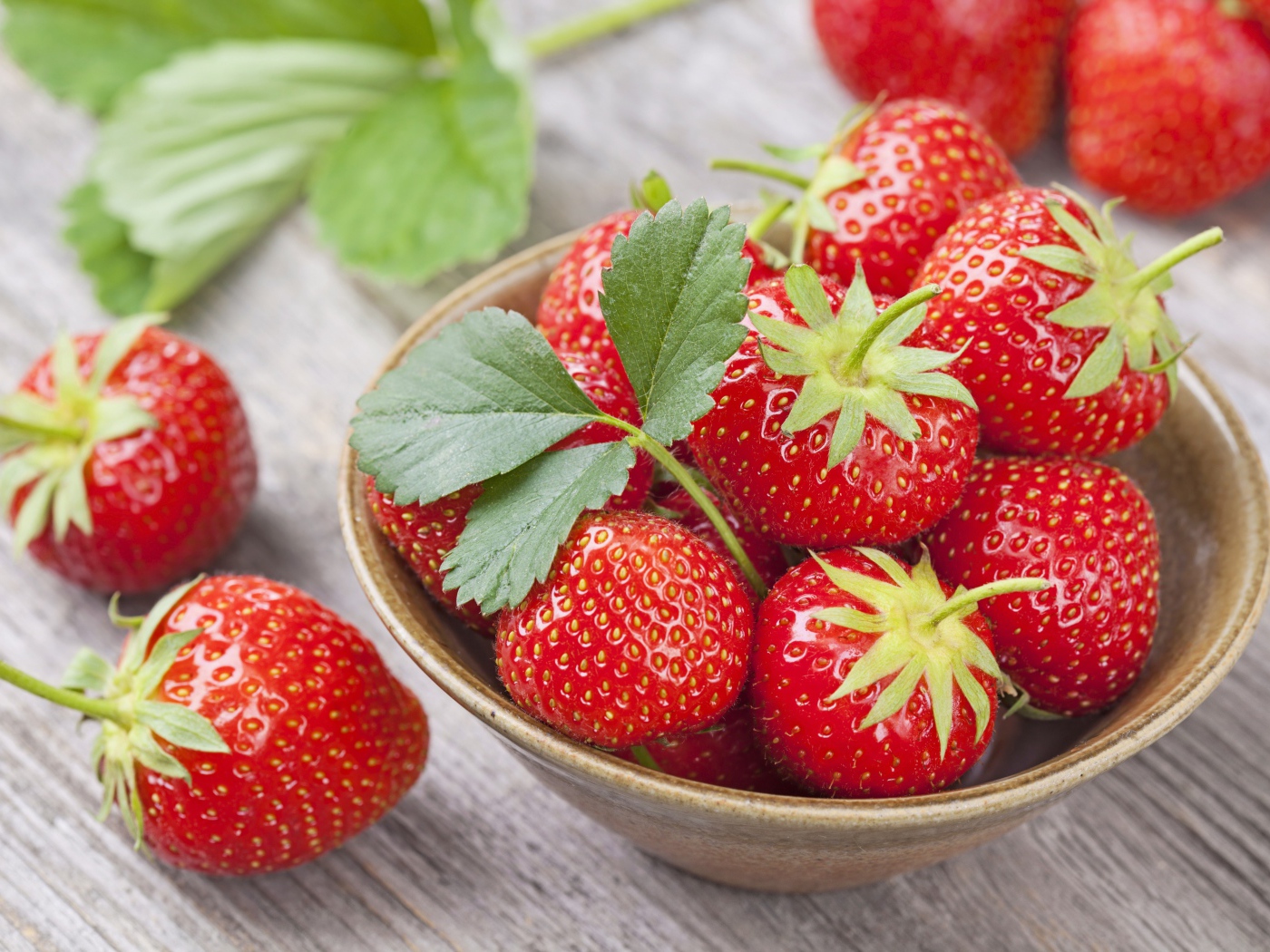 Красная спелая сладкая клубника в тарелке с зелеными листьями