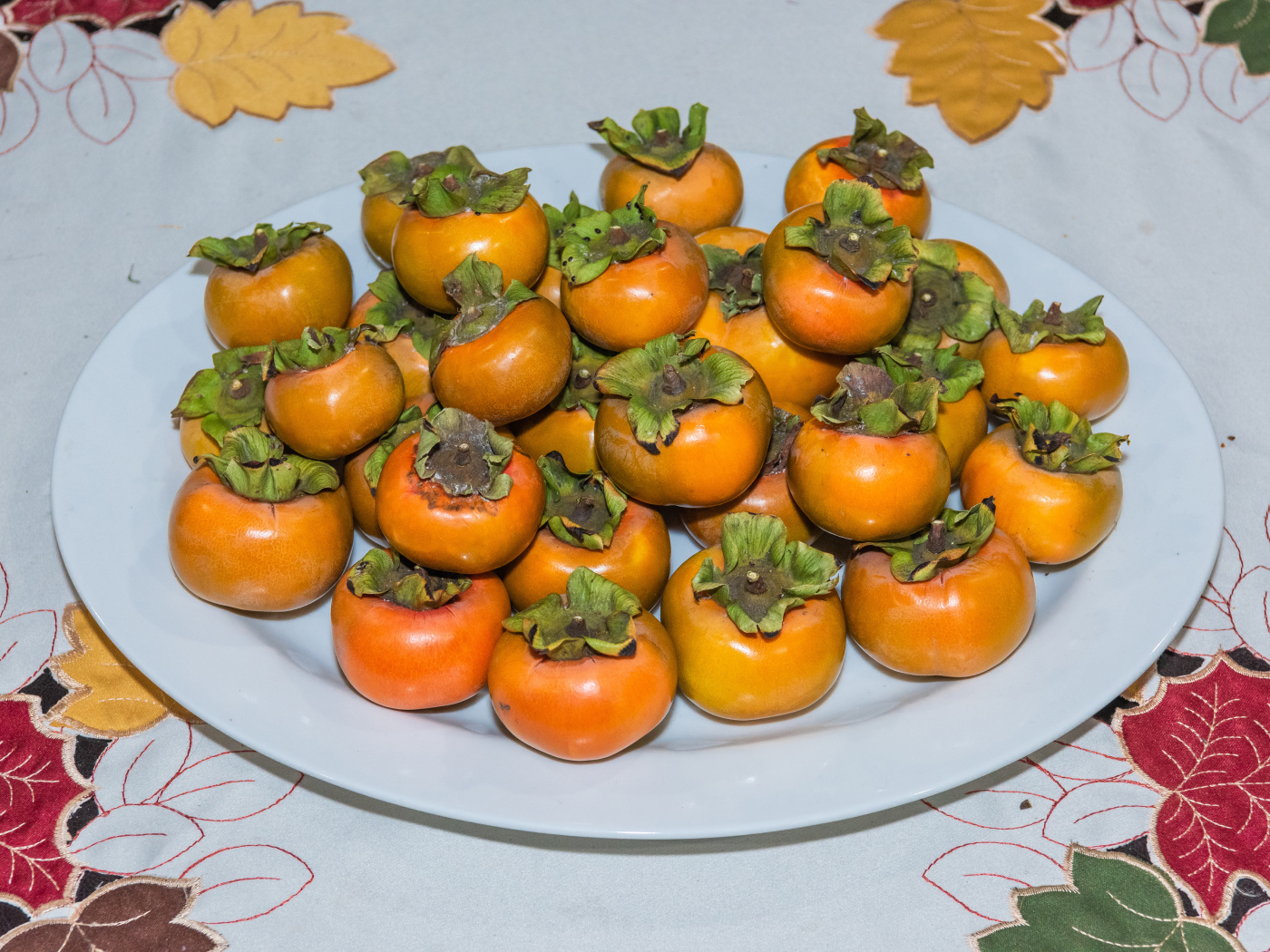 Спелый фрукт хурма на большой белой тарелке 