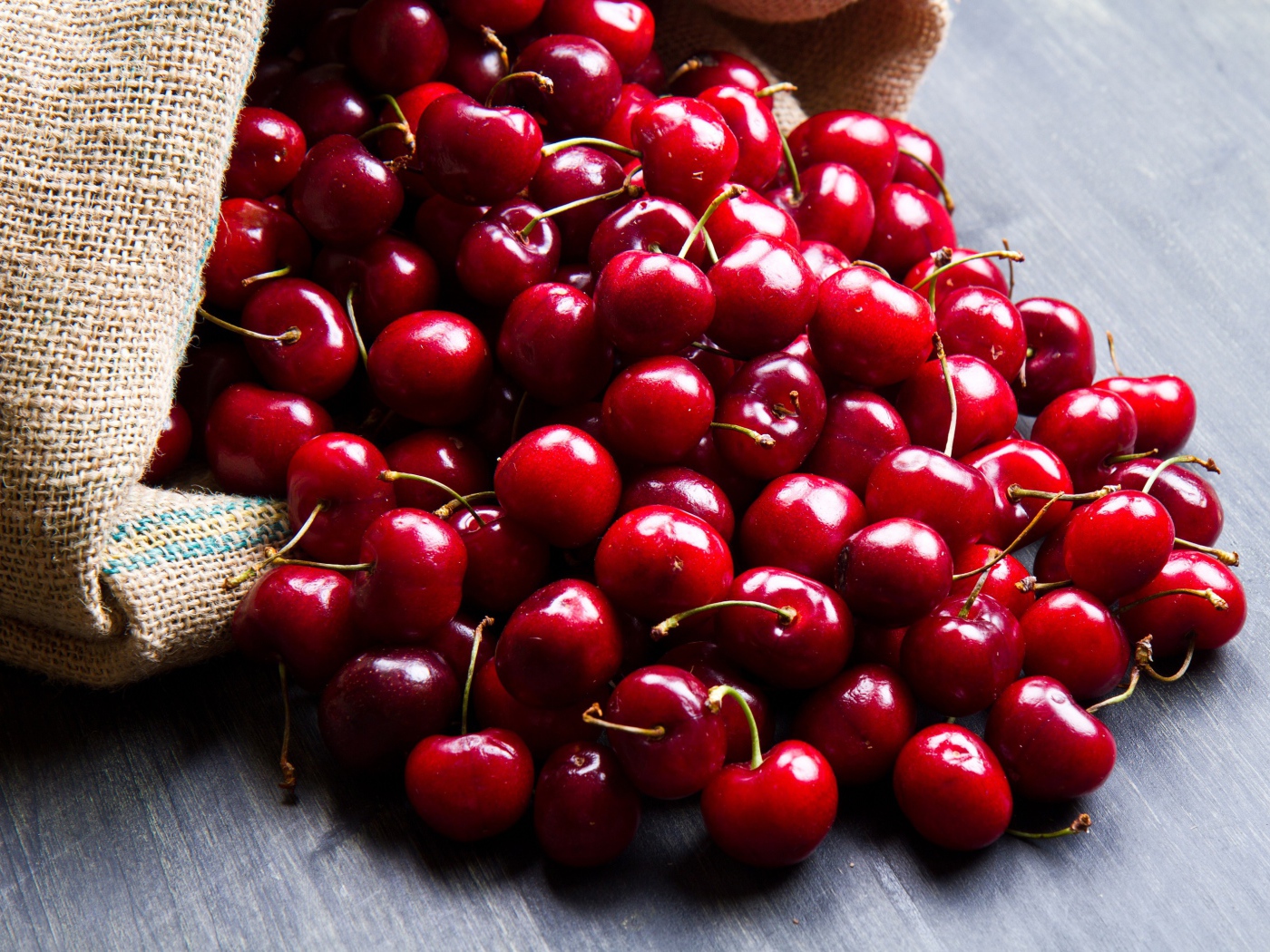 Спелые красные черешни в мешке на столе 