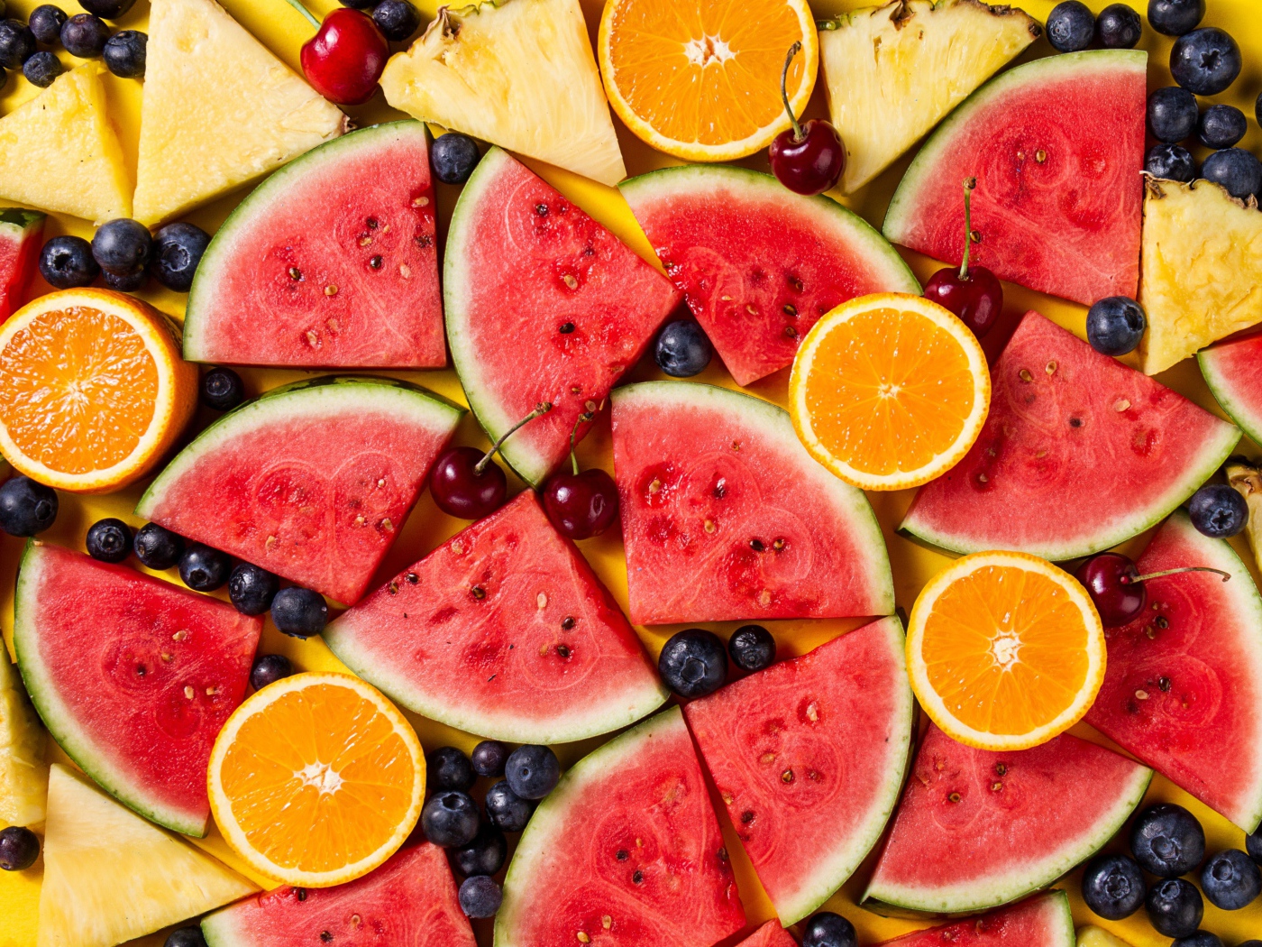 Кусочки арбуза, ананаса и апельсина с ягодами вишни и черники 