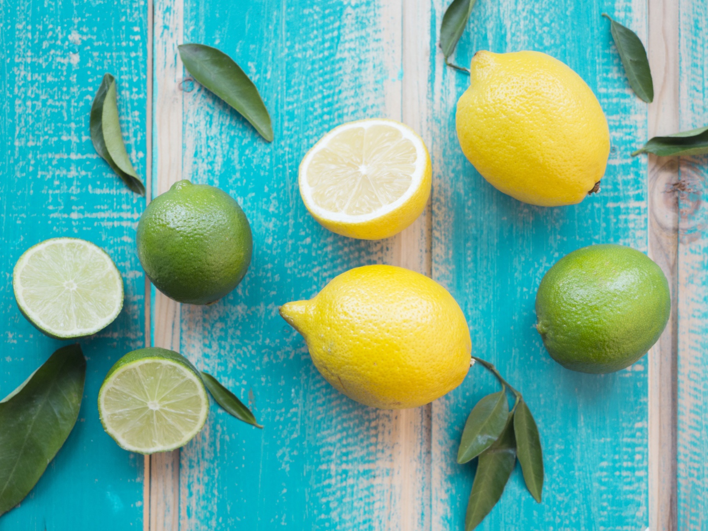 Желтые лимоны и зеленые плоды лайма на столе 