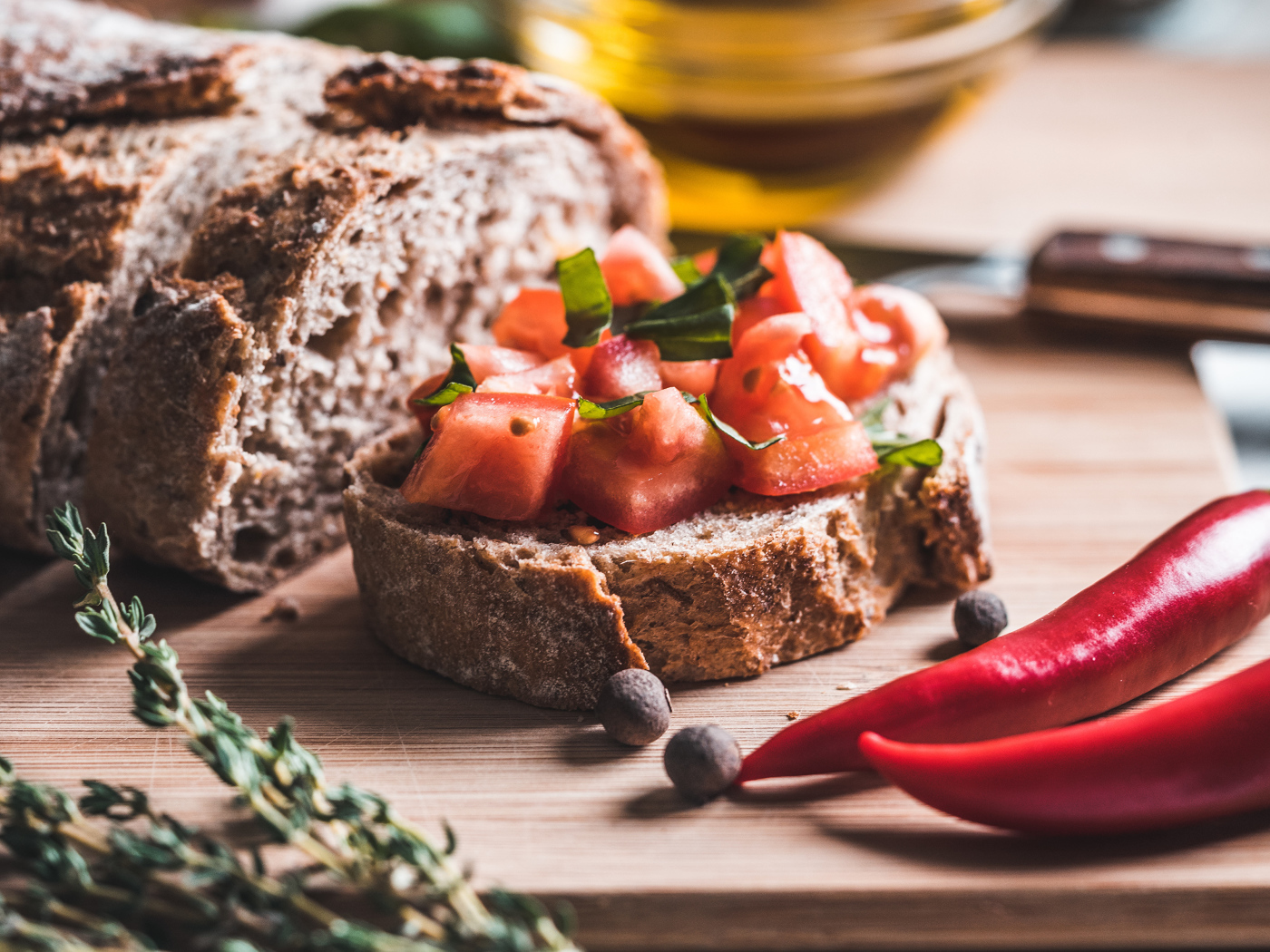 Черный хлеб с кусочками помидора на столе с острым красным перцем