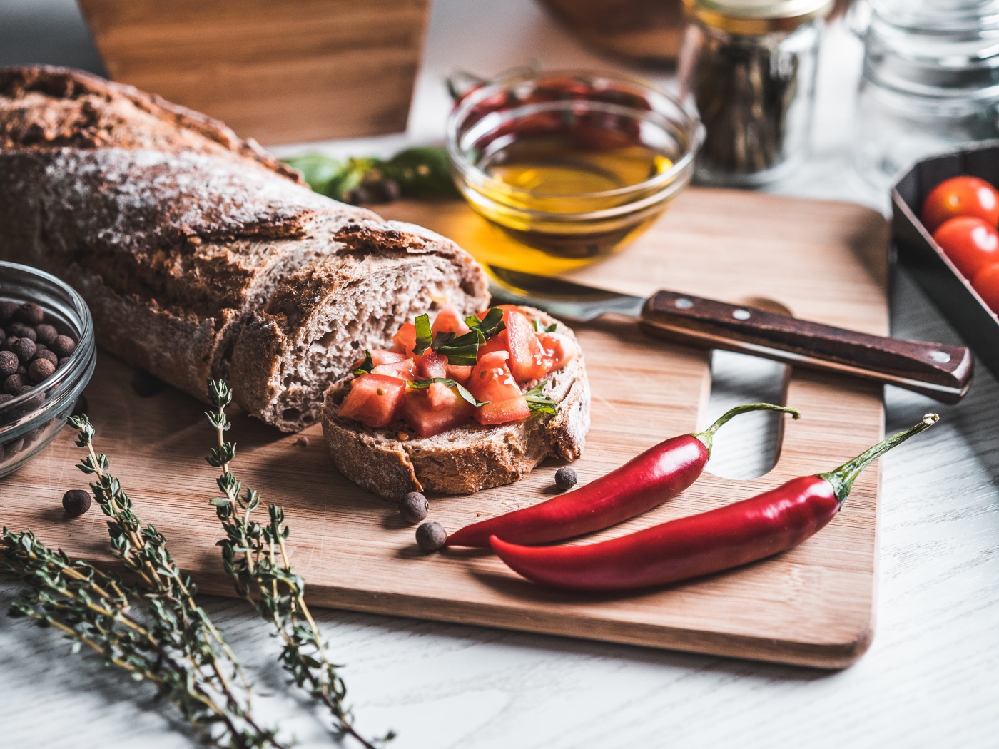 Батон с помидорами и красным перцем на столе с маслом