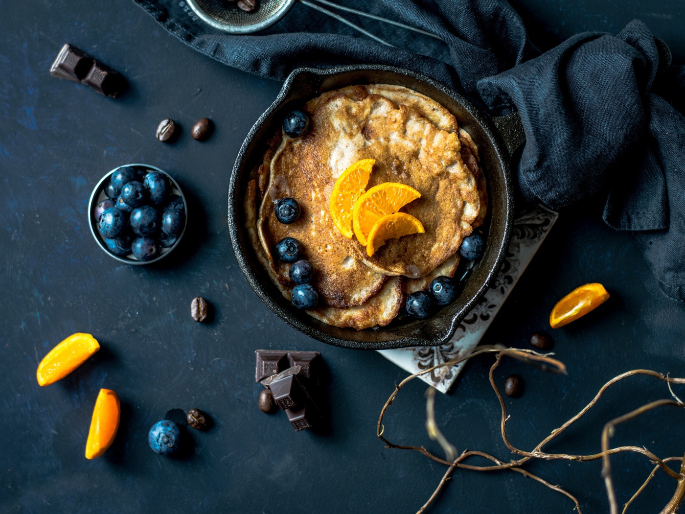 Блины с ягодами черники и апельсинами на столе 