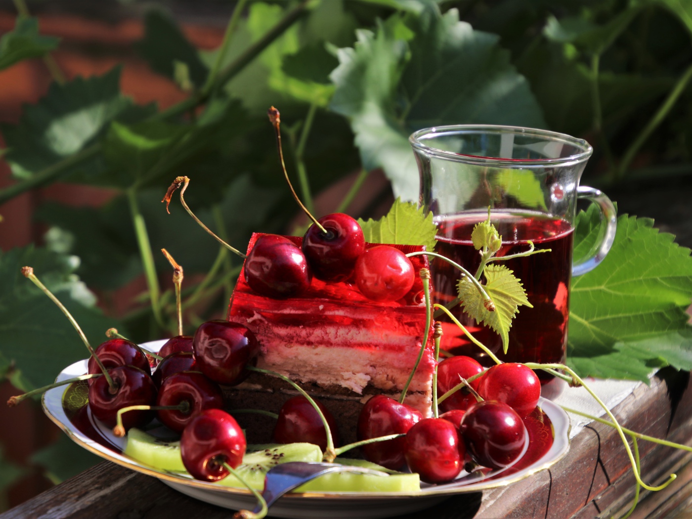 Кусок торта с черешней на столе с чашкой чая 