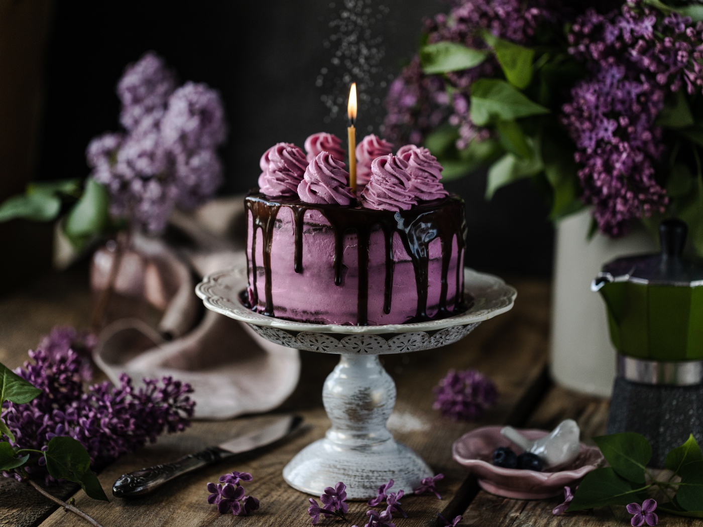 Ягодный торт со свечой на столе с сиренью 