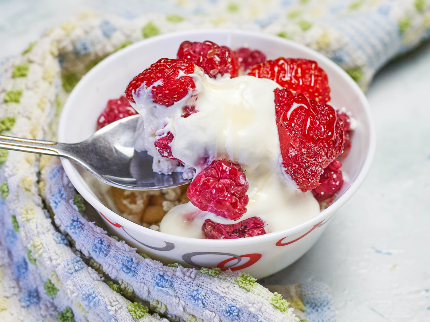 Завтрак с йогуртом и малиной в миске с ложкой